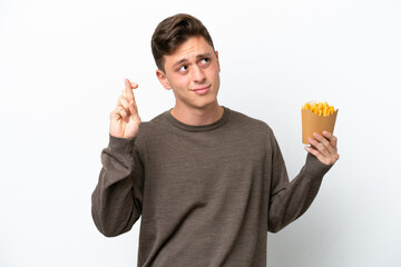 Young Brazilian man holding fried chips isolated on white background with fingers crossing and wishing the best