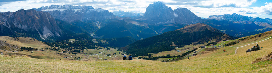Fototapeta na wymiar Couple sitting overlooking Dolomites in European Alps. Gardena Pass, Italy