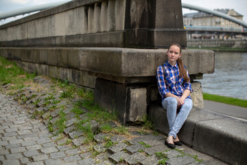 A teen girl sits on the city promenade. Krakow, Poland.