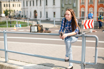 Fototapeta premium A girl is standing on the street near the road repair.