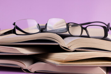 Opened books with glasses on pink background. Study, education and back to school concept.