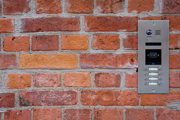 Video intercom on red brick wall background. Modern, luxury, wealthy home security system. Alarm...
