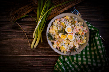 olivier salad, green onions on wooden background