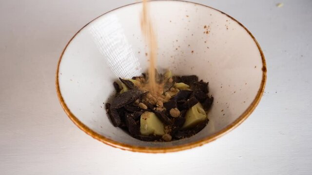 Making chocolate bar, adding cocoa sugar powder to cocoa butter into a bowl.