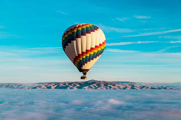 Hot air balloons flying over spectacular Cappadocia. Beautiful view of hot air balloons floating in sunrise blue sky over the mountain landscape of fairy chimneys