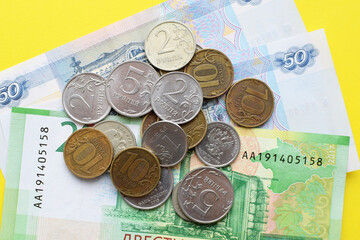 Money of Russia. Banknotes and coins on yellow background. Close-up of Russian rubles of various denominations.