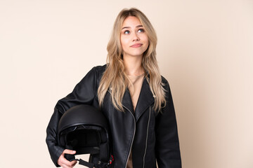 Russian girl with a motorcycle helmet isolated on beige background and looking up