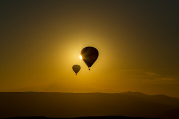 Hot air balloons flying over spectacular Cappadocia. Beautiful view of hot air balloons floating in sunrise blue sky over the mountain landscape of fairy chimneys