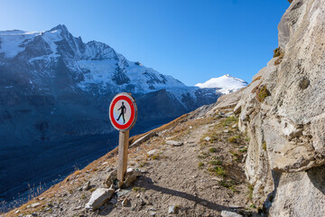 No access sign on difficult mountain path with snowy peak in background