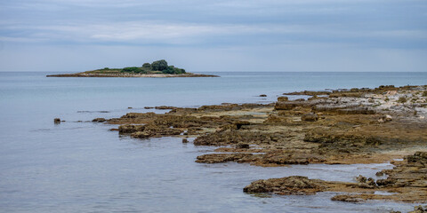 Fototapeta na wymiar Small rocky island with rocky shore in foreground