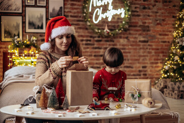 a happy family mother and child pack Christmas gifts