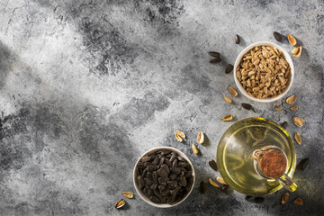Sunflower seeds in a bowl with cooking oil on concrete background. Concept of food industry.