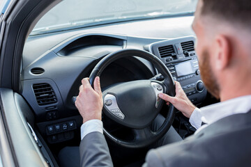 Close-up photo of man's hand switching car mode on steering wheel buttons