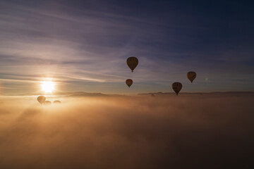 Hot air balloons flying over spectacular Cappadocia. Beautiful view of hot air balloons floating in sunrise blue sky over the mountain landscape of fairy chimneys