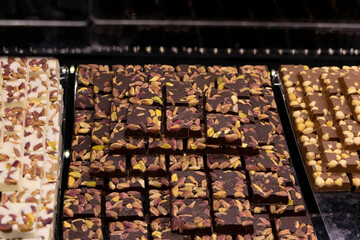 Chocolate bars on a dark background with pistachios, almonds and nuts. Delicious, tasty dessert.