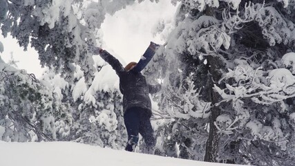 Boy throwing snow into the air. The child who grabs the snow from the ground throws it into the air and plays with both hands outstretched.