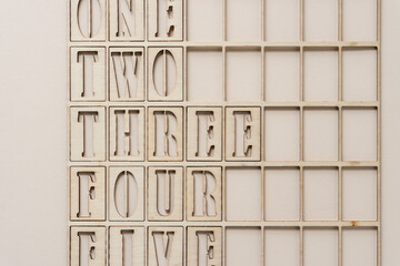 the numbers one, two, three, four, five (some partly cut off) spelled out and arranged inside a wooden grid
