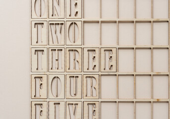 the numbers one, two, three, four, five (some partly cut off) spelled out and arranged inside a wooden grid