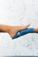 Close up of a podiatrist hands with medical gloves exploring the foot of a patient in the podiatry clinic.
