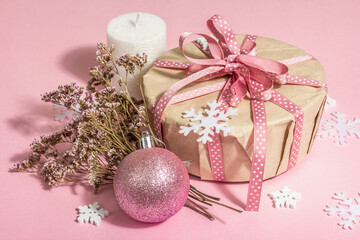 Christmas or New Year gift concept in pink tones. Wrapper box, tied bow, flowers, and festive toy