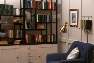Cozy home library interior with collection of different books on shelves and comfortable place for...