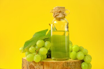 Grape seed oil.Base cosmetic oil for massage and care for face and body. bottle and bunch of green grapes on a bright yellow background.Organic Natural Grape Seed Oil.natural cosmetics