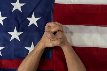 A man praying for his country over the United States flag