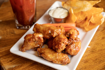 A plate of chicken wings with potato chips and a Canadian Caesar cocktail.