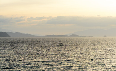 A gorgeous sunset over the Pacific Ocean with rain over the outlying islands and puffy clouds. 