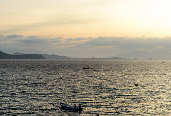 A gorgeous sunset over the Pacific Ocean with rain over the outlying islands and puffy clouds. 