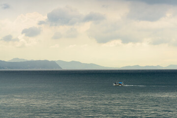 A gorgeous sunset over the Pacific Ocean with rain over the outlying islands and puffy clouds. 
