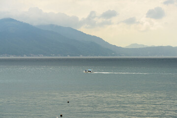 Obraz premium A gorgeous sunset over the Pacific Ocean with rain over the outlying islands and puffy clouds. 