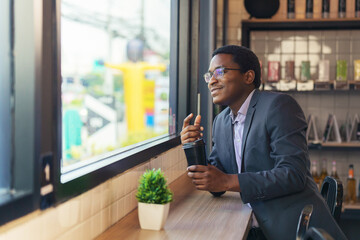 businessman sitting at counter by window in coffee shop holding coffee cup
