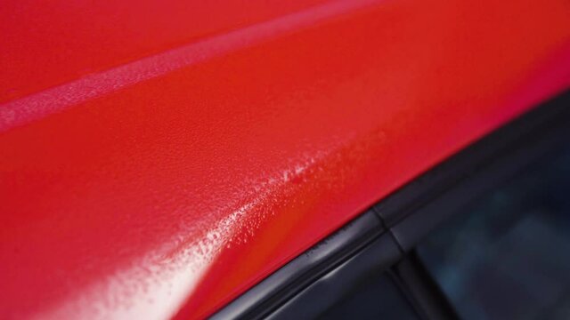 Red car with wet paint job detail shot in slow motion