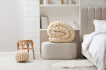 Soft chunky knit blanket and pouf in stylish room interior
