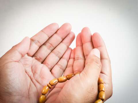 Close up praying hands with prayer beads isolated on white background.