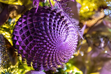 Closeup of sparkly purple Christmas ornament hanging on a tree