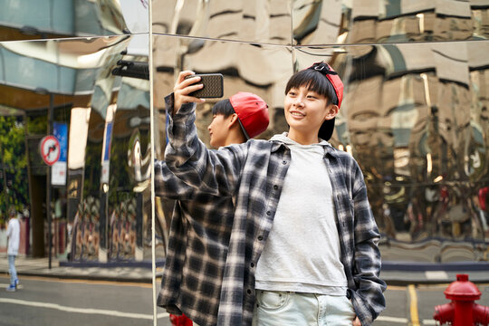 teenage asian boy taking a selfie outdoors on street