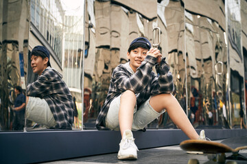 teenage asian child skateboarder relaxing on street