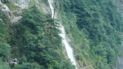 The beautiful countryside view with the waterfall flowing in the mountains after the rainy day