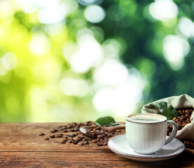 Cup of aromatic hot coffee and beans on wooden table outdoors. Space for text