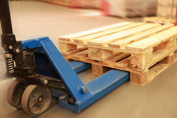 Fototapeta na wymiar Modern manual forklift with wooden pallets in warehouse, closeup