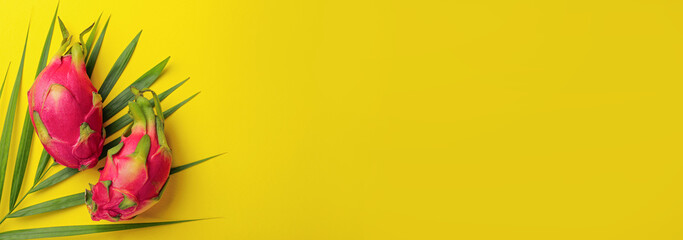 Delicious dragon fruits (pitahaya) and palm leaf on yellow background, flat lay with space for text. Banner design