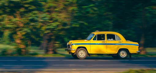 Ambassador Car made Yellow Taxi for Public transport.  Panning Shot is taken.