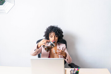 latin woman serving cup of coffee with french press in office