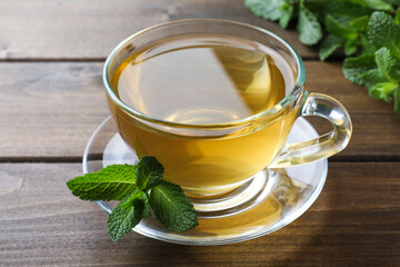Cup of aromatic green tea with fresh mint on wooden table