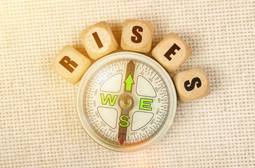 On the table is a compass and cubes with the inscription - RISES
