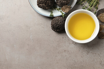 Fresh truffles, oil in bowl and thyme on light grey table, flat lay. Space for text