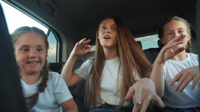 children teenagers dancing in the car on the road travel. happy family adventure a kid dream concept. friendly family sisters fun dancing having to the music in the car on the way to vacation
