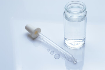 glass transparent jar and a cosmetic pipette with liquid droplets on a white background.